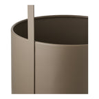 Détail du bord d'un cache-pot en acier taupe mat et de son anse plate fixée le long du flanc