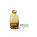 Carafe en verre ambré vue en plongée sur son col ouvert avec le bouchon couché à côté