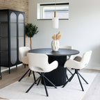 Chaises Amorim pivotantes bouclé blanc cassé autour table ronde noire cannelée avec vitrine et suspension