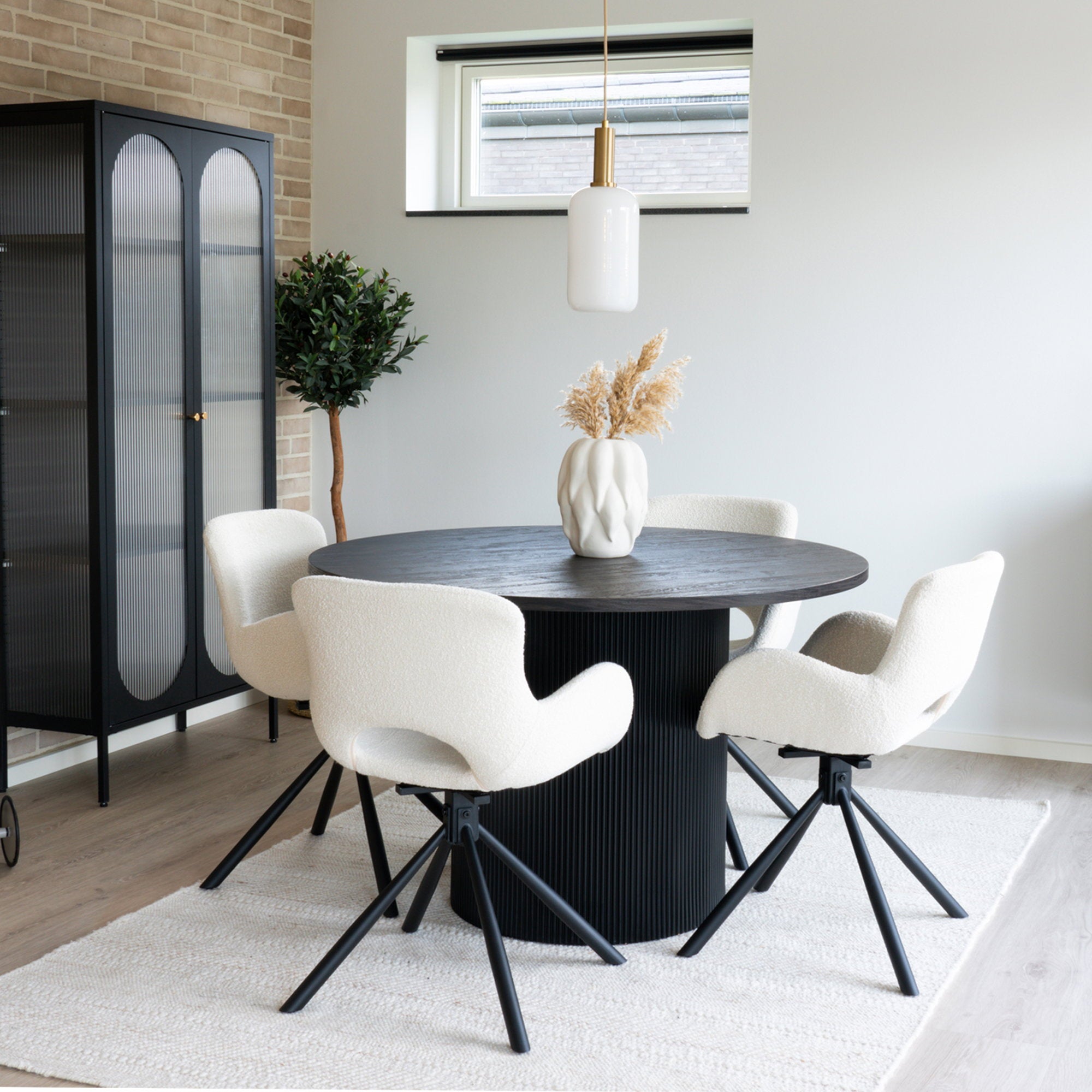 Chaises Amorim pivotantes bouclé blanc cassé autour table ronde noire cannelée avec vitrine et suspension