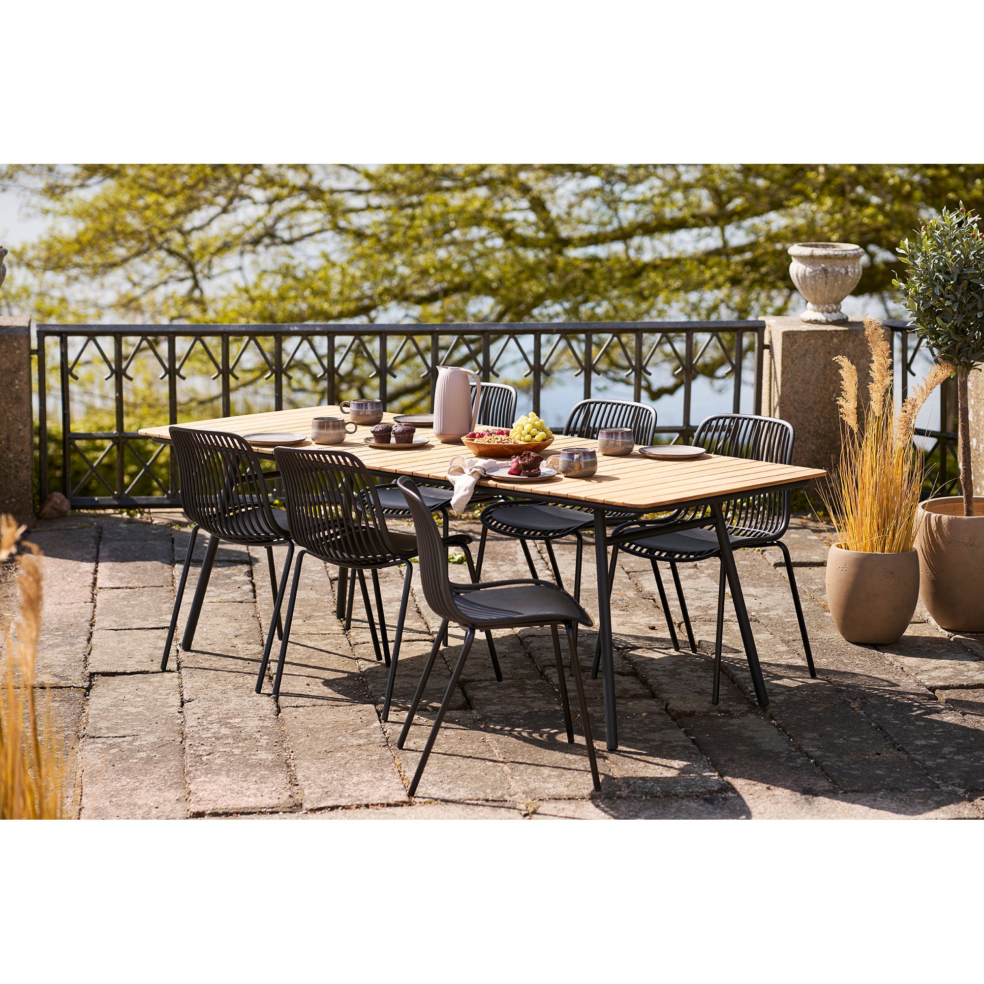 Chaises Branson noires autour table teck terrasse jardin ensoleillé