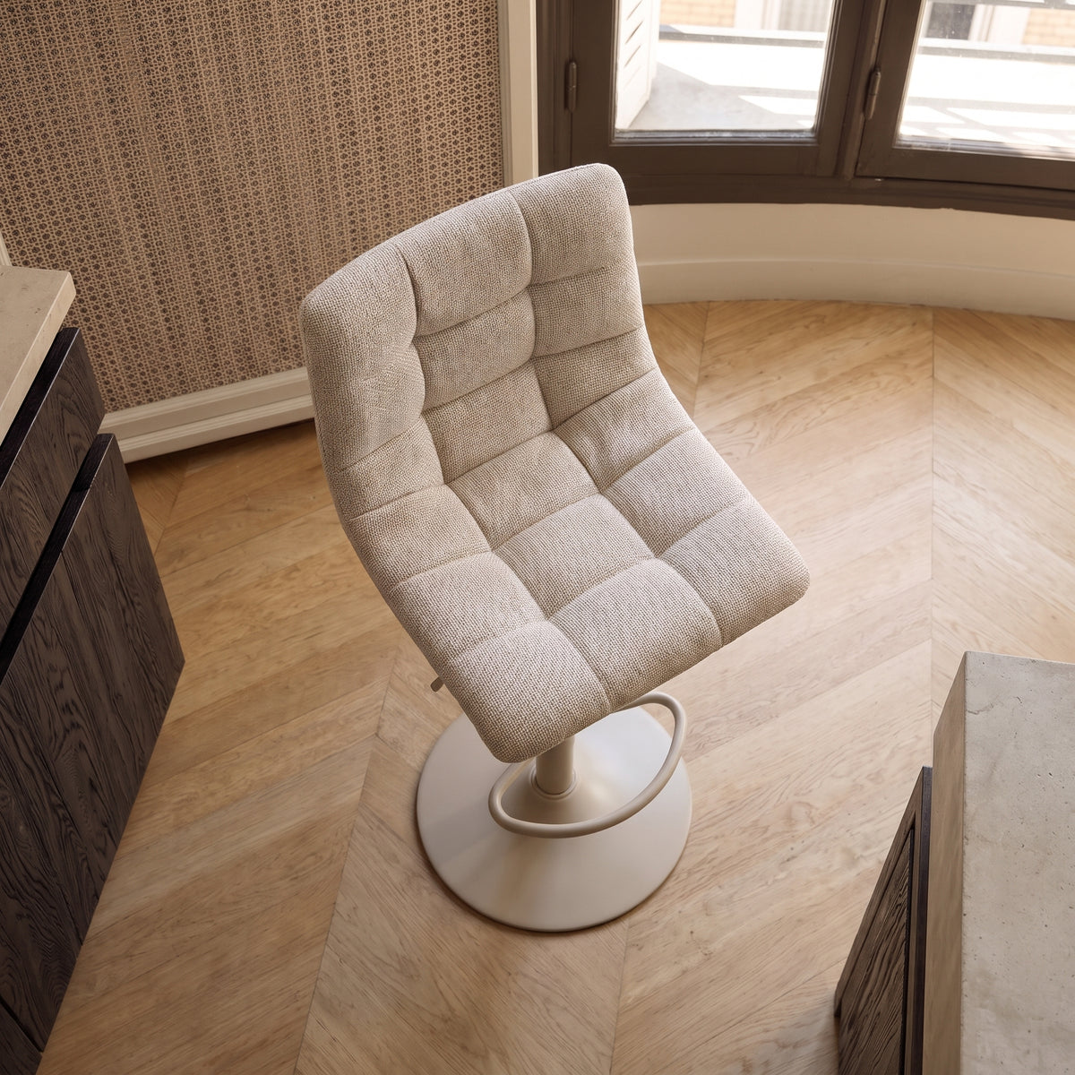 Chaise de bar Middelfart en tissu gris vue de dessus, assise pivotée, sur un parquet en chevrons près d'un plan de travail
