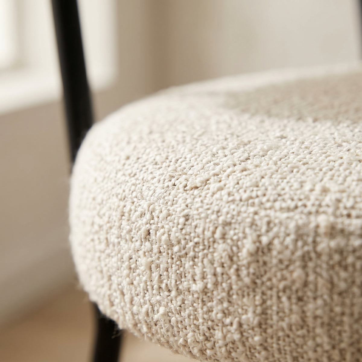 Gros plan sur l'assise ronde en bouclé blanc de la chaise Badalona