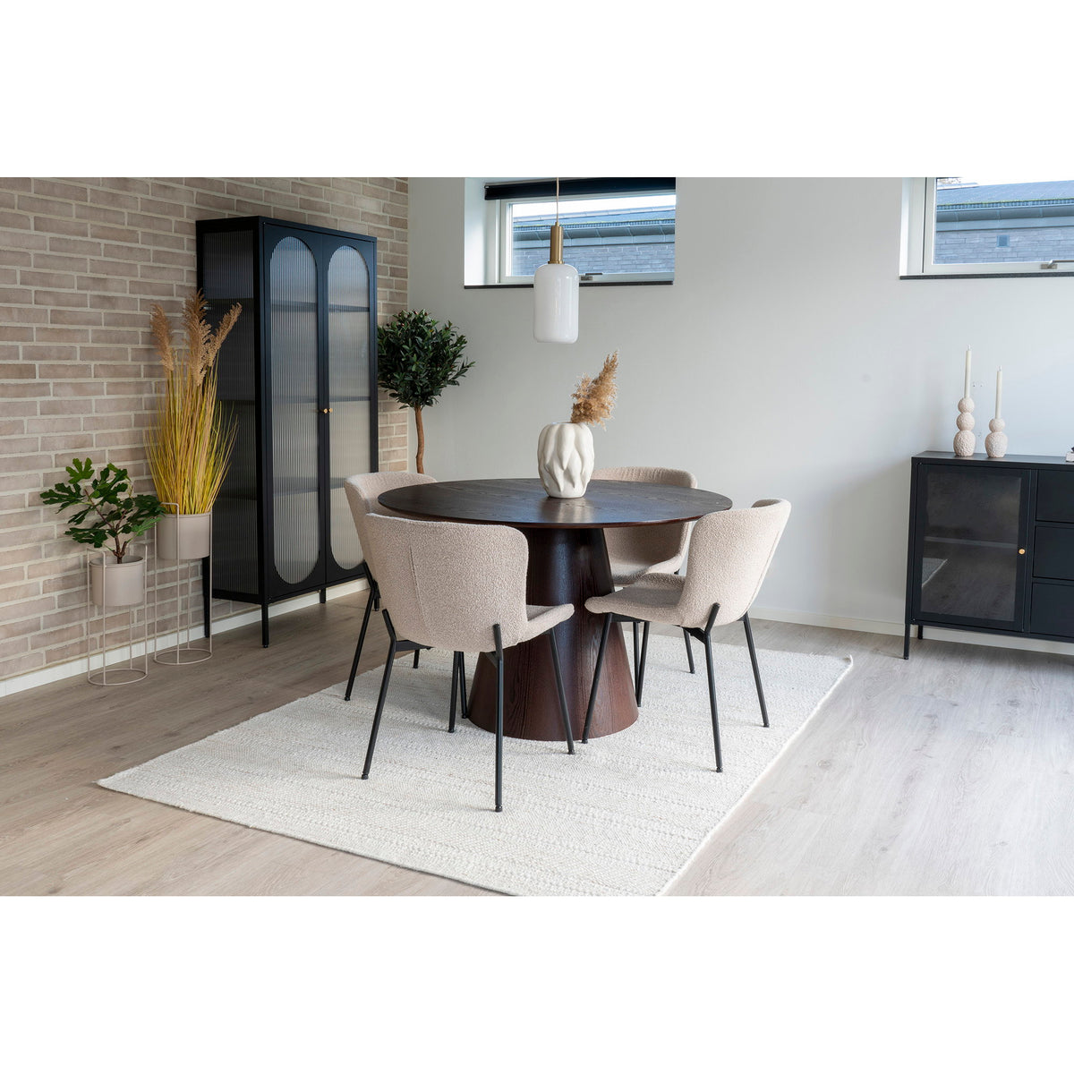 Quatre chaises Maceda bouclé taupe autour d'une table ronde en bois sombre sous une suspension en verre blanc