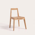 Chaise Paxi en teck naturel vue de trois quarts sur fond clair, assise à lattes et dossier en bandeau