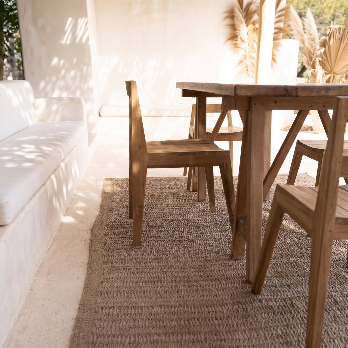 Chaises Paxi en teck naturel autour d'une table en bois, sur un tapis en fibres naturelles