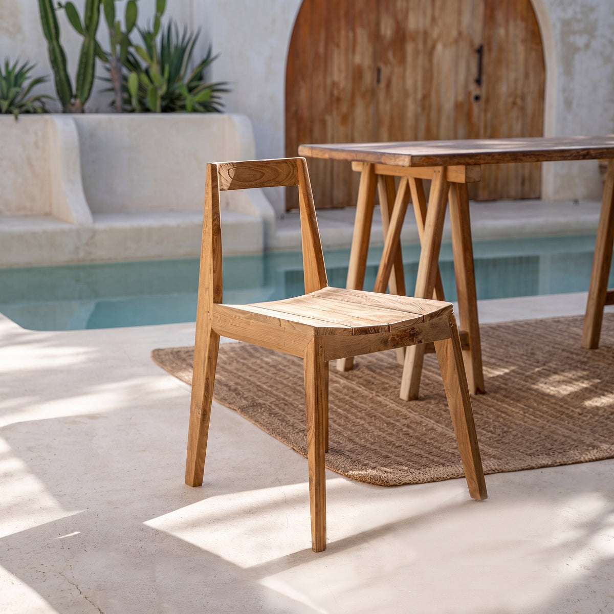 Chaise Paxi en teck naturel au bord d'une piscine, devant une table en bois sur tréteaux