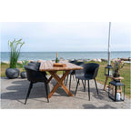 Six chaises Roda noires autour d'une table en bois sur une terrasse au bord de la mer