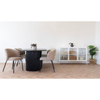 Chaises Safira bouclé beige autour d'une table ovale noire à pied cannelé près d'un buffet vitré blanc