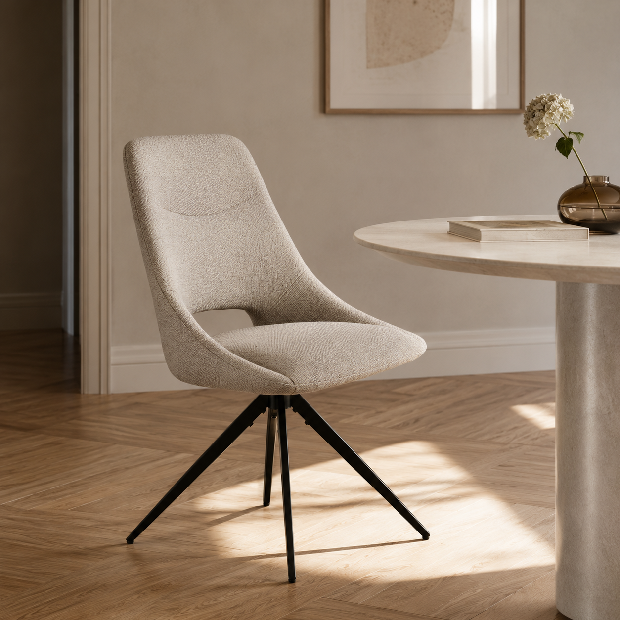Chaise de salle à manger pivotante Dokka en tissu chiné sable à piètement étoile noir, près d'une table ronde dans un intérieur lumineux