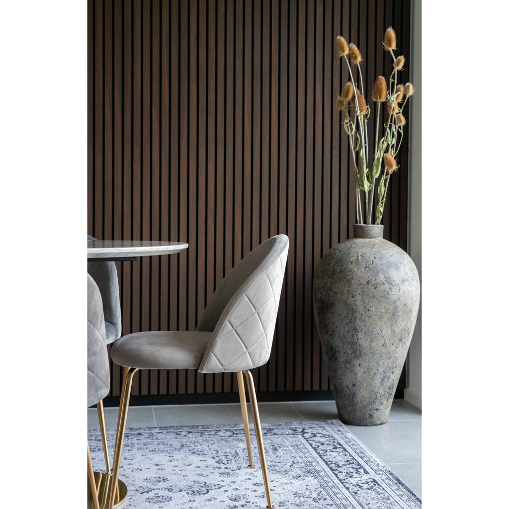 Détail profil chaise Geneve velours gris piqûre losange et pieds laiton brossé table marbre