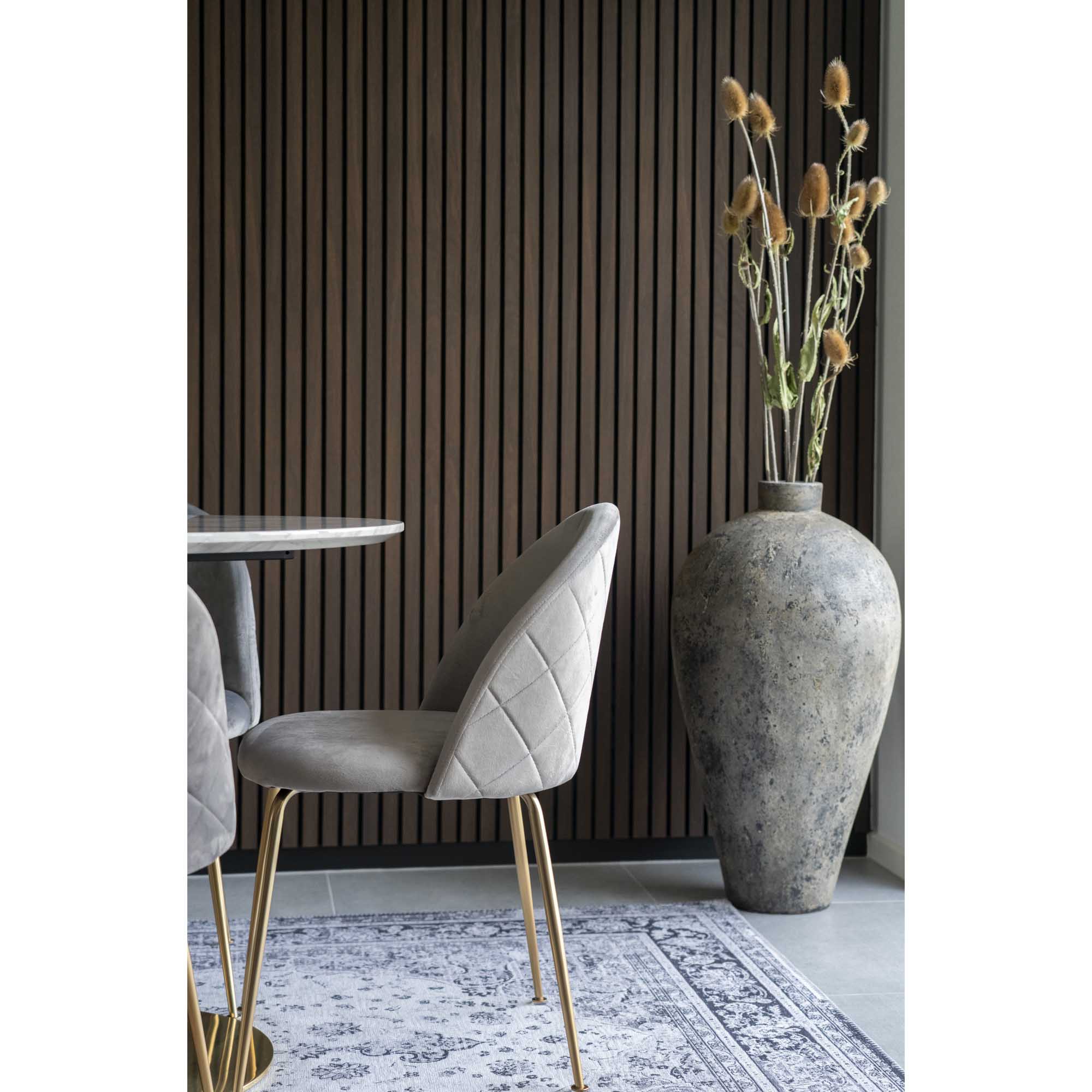 Détail profil chaise Geneve velours gris piqûre losange et pieds laiton brossé table marbre