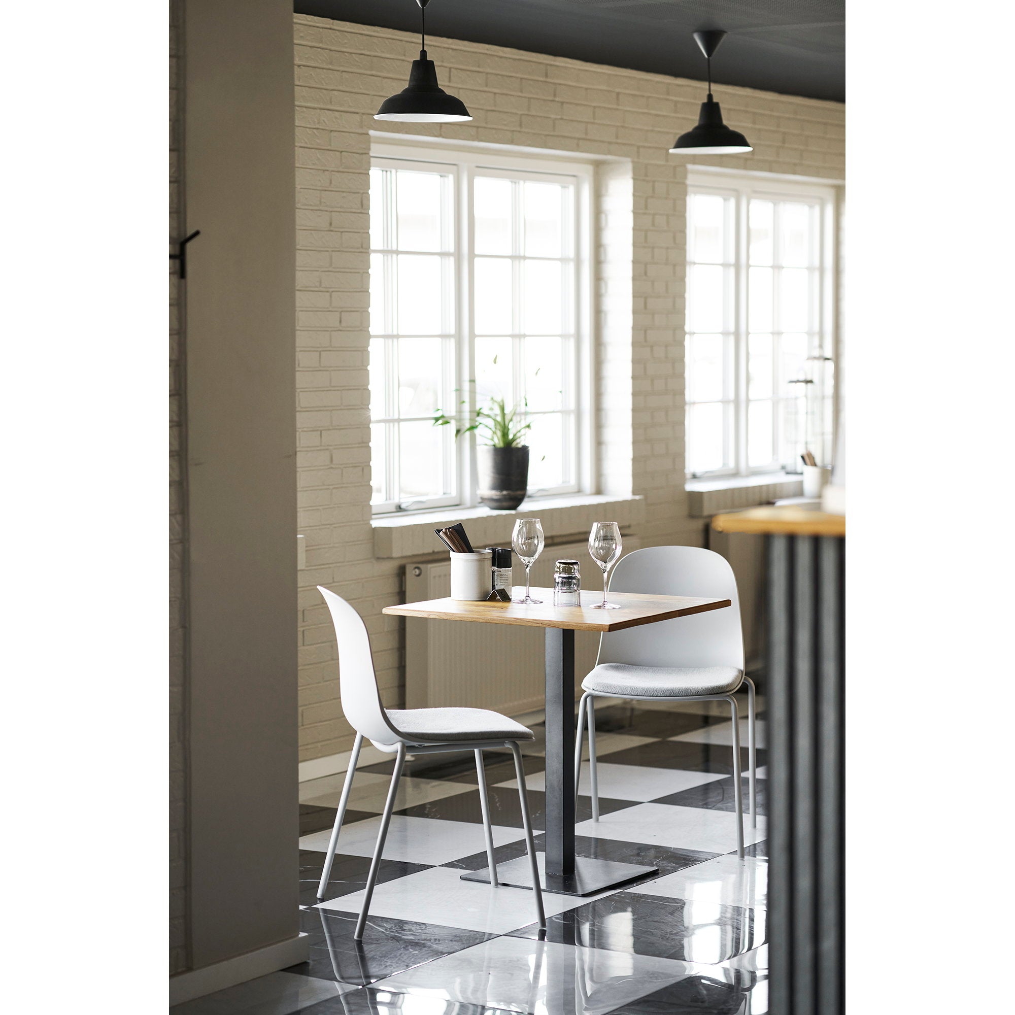 Deux chaises Madalena gris clair autour d'une table bistrot dans espace restaurant contemporain