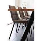 Gros plan chaises Middelfart microfibre brun clair matelassées sous table bois massif pieds métal noir