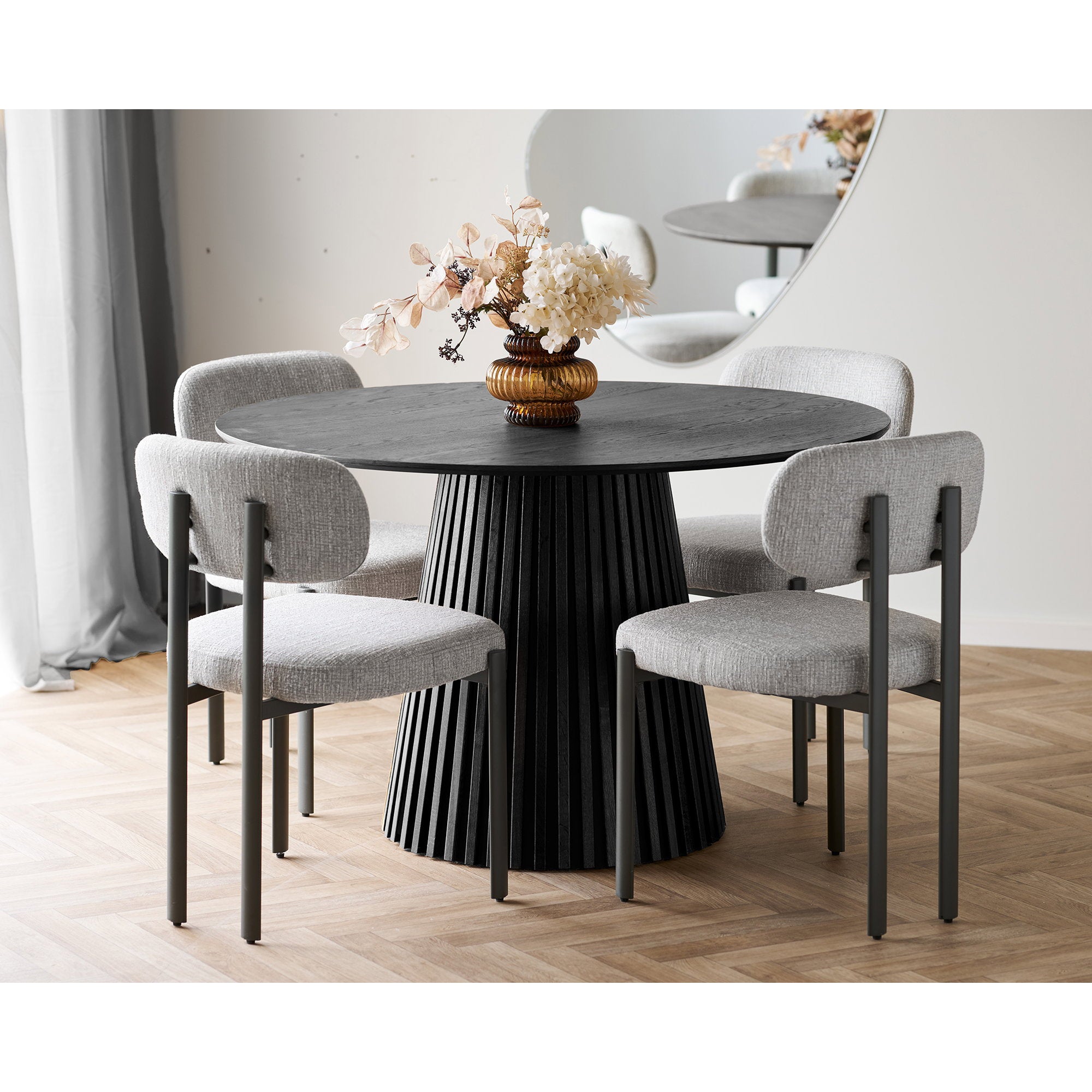 Ambiance salle à manger 4 chaises Royan gris clair autour d'une table ronde noire nervurée