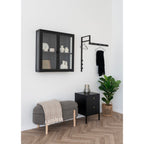 Cintres métal noir Massa sur portant mural noir en intérieur industriel avec meuble vitrine