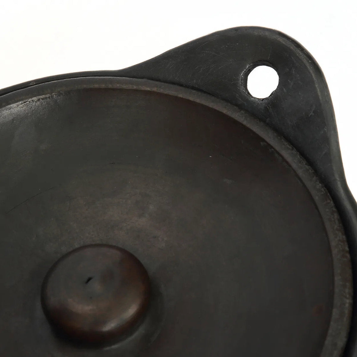 Détail du bouton du couvercle et d'une anse percée de la cocotte en terre cuite noire