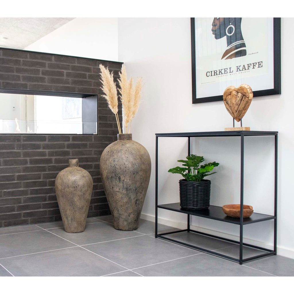 Console Vita noir mise en scène entrée vases pierre brute herbes pampas mur briques