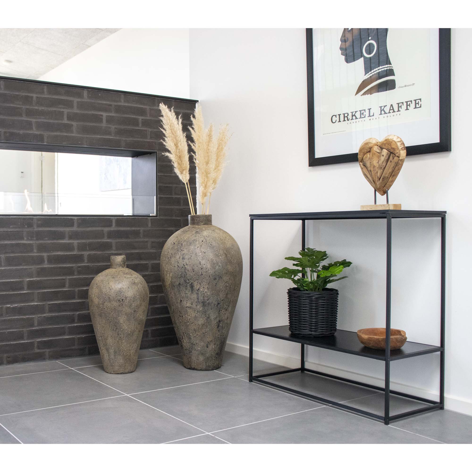 Console Vita noir mise en scène entrée vases pierre brute herbes pampas mur briques