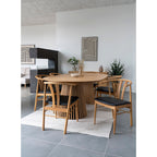 Salle à manger avec la coupe plissée beige posée sur une table ovale en bois à pied à lattes entourée de chaises en bois