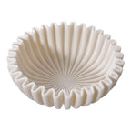 Vue plongeante sur l'intérieur de la coupe plissée beige et ses plis qui rayonnent du centre du fond
