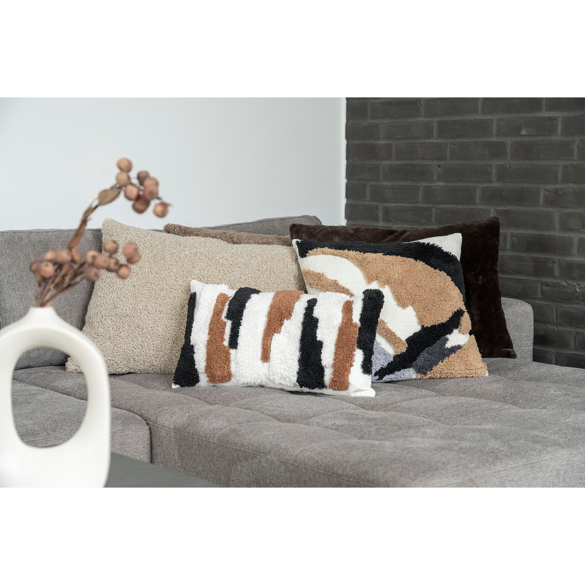 Coussin Tavira bouclé gris-brun rectangulaire posé sur canapé gris décor contemporain