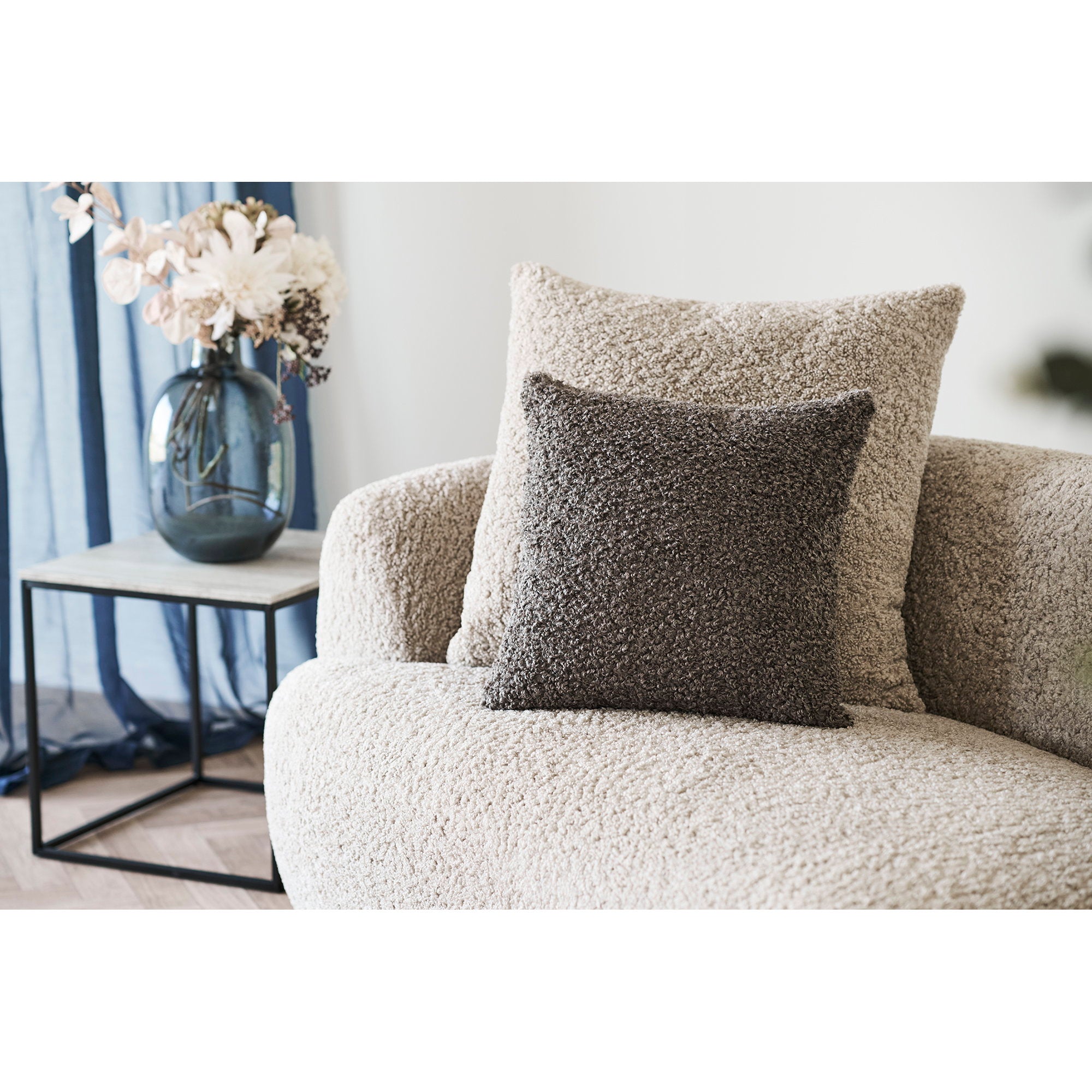 Coussin Tavira bouclé gris anthracite posé sur canapé bouclette beige décor contemporain