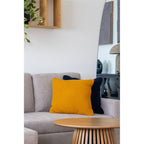 Coussin Santos ocre moutarde tricot posé sur canapé gris décor contemporain
