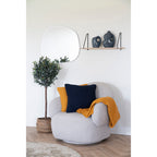 Coussin Santos ocre moutarde associé coussin bleu marine fauteuil bouclette décor épuré