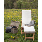Coussin Arrecife blanc sur une chaise longue en bois vue de face dans une prairie