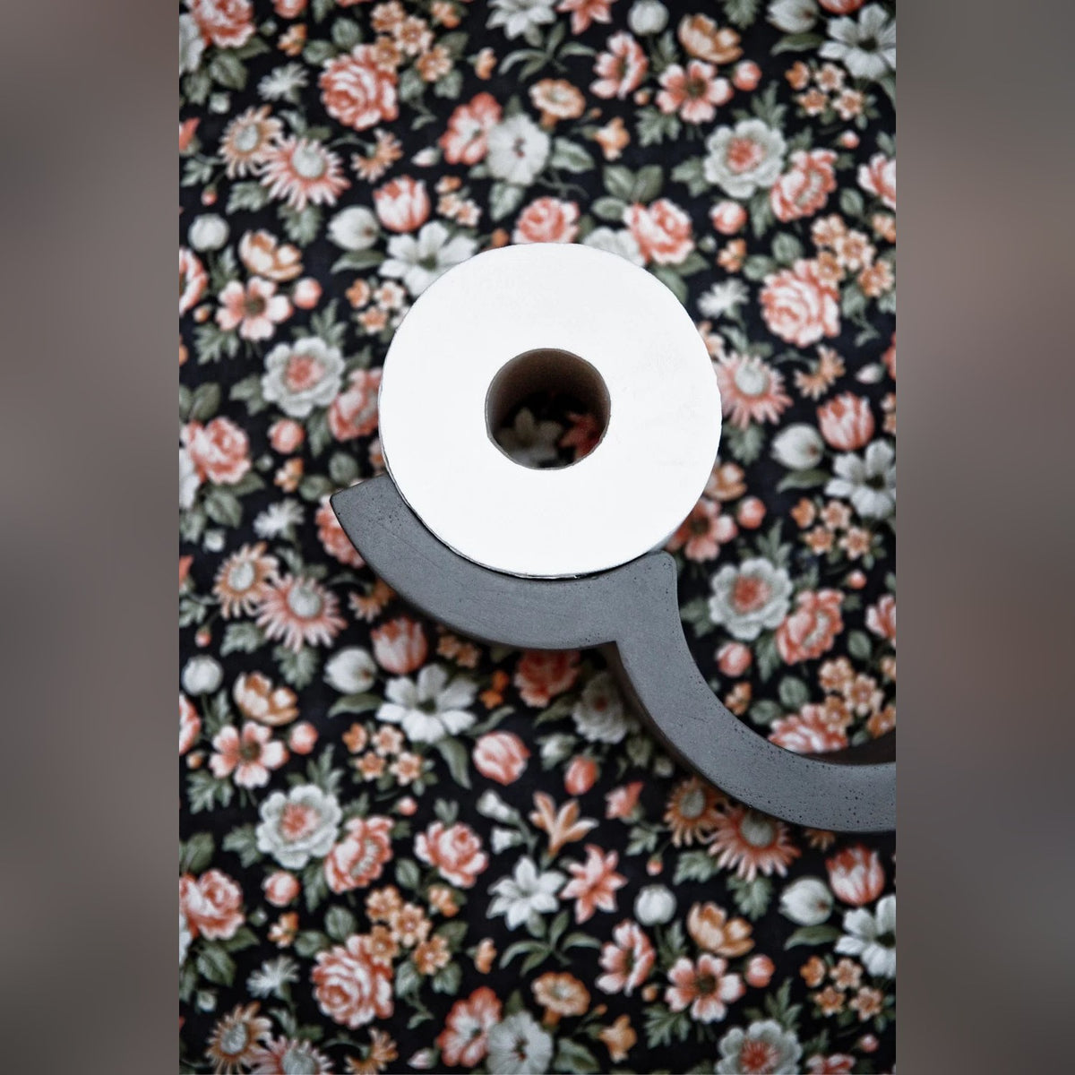 Dérouleur Cloud en béton avec un rouleau sur un mur tapissé de papier peint fleuri