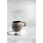 Tasse en grès émaillé posée sur le dessous-de-plat croix en marbre blanc