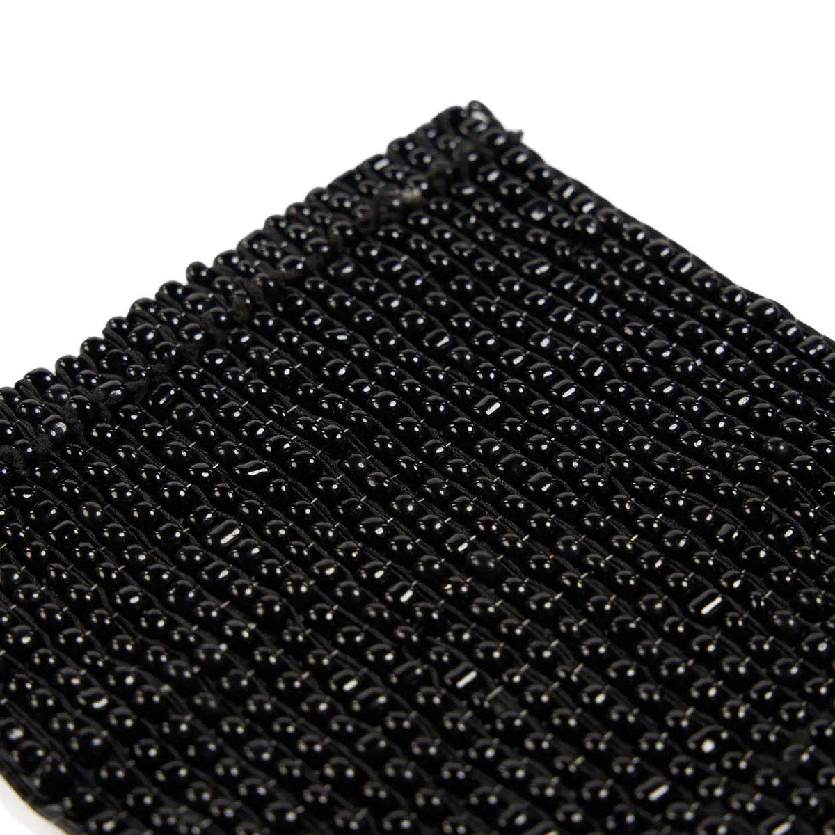 Détail des perles noires brillantes alignées en rangs serrés du dessous-de-verre carré