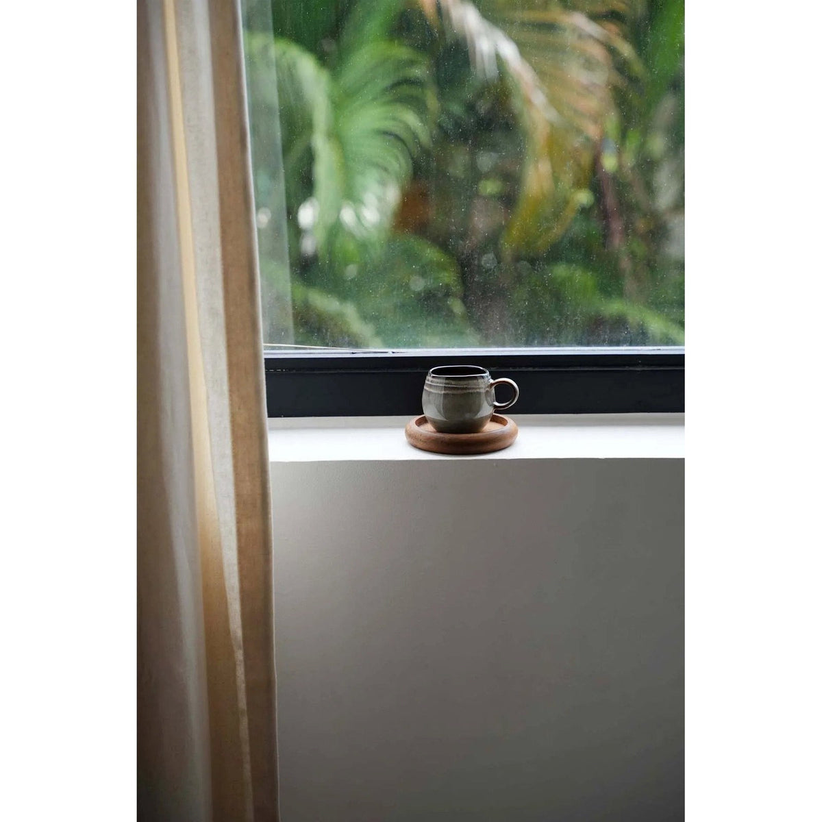 Tasse en céramique posée sur le dessous-de-verre VIP en teck naturel sur un rebord de fenêtre