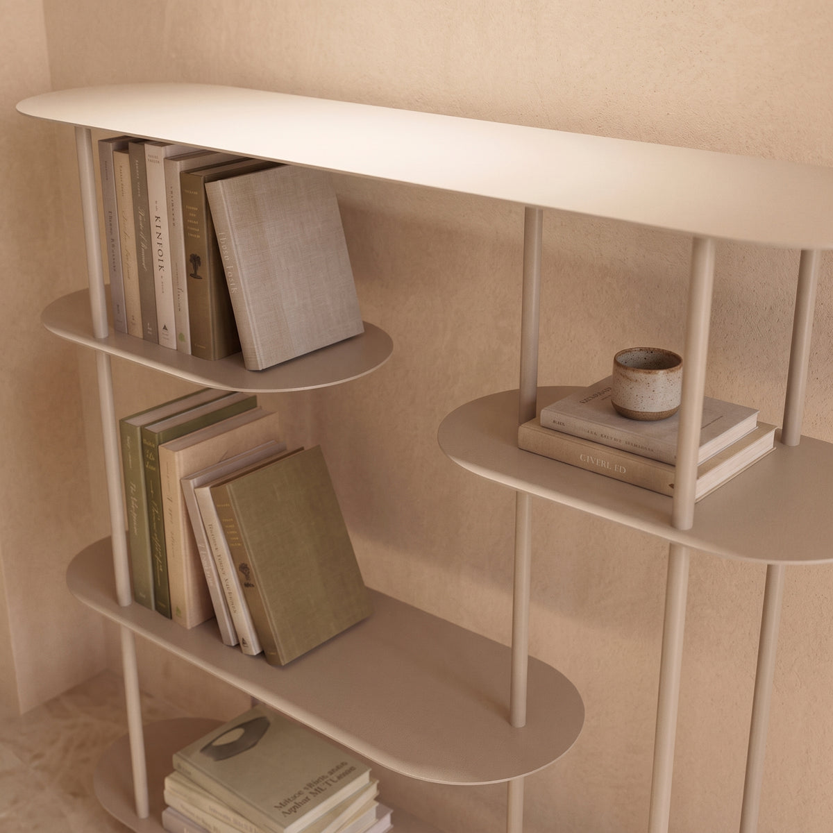 Vue plongeante sur les plateaux décalés de l'étagère console Rieti sable, garnis de livres et d'une tasse en grès