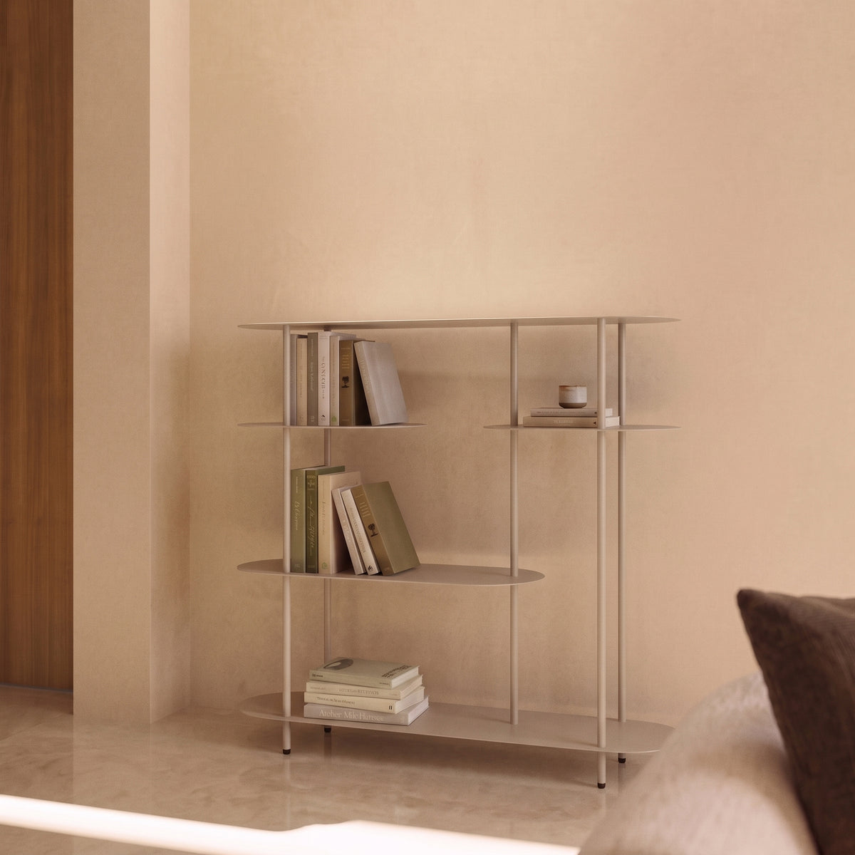 Étagère console Rieti en métal sable garnie de livres contre un mur beige