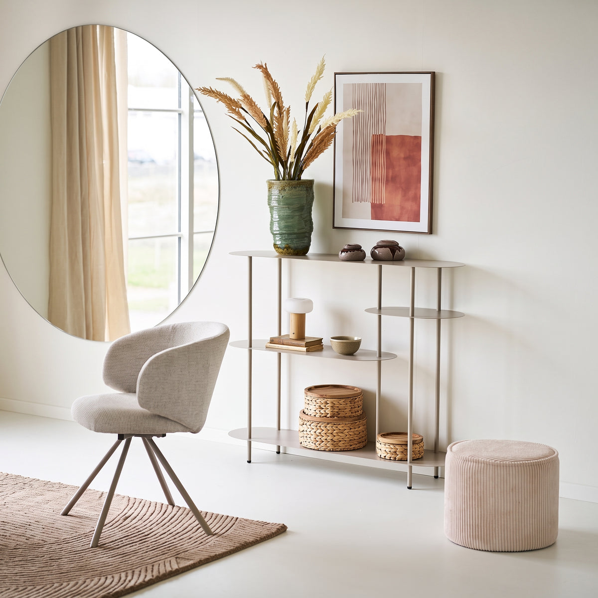 Étagère console Rieti en métal sable dans un séjour lumineux, entre un grand miroir rond, un fauteuil et un pouf