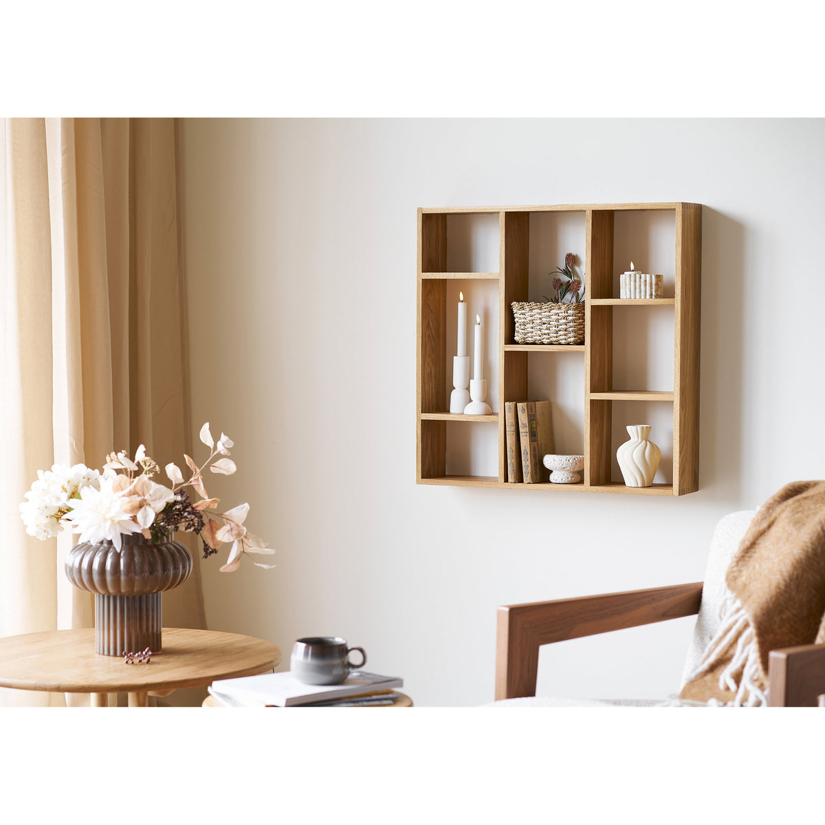 Étagère Townsville chêne naturel fixée au mur d'un salon avec bougeoirs blancs panier tressé livres et vase près d'un fauteuil en bois