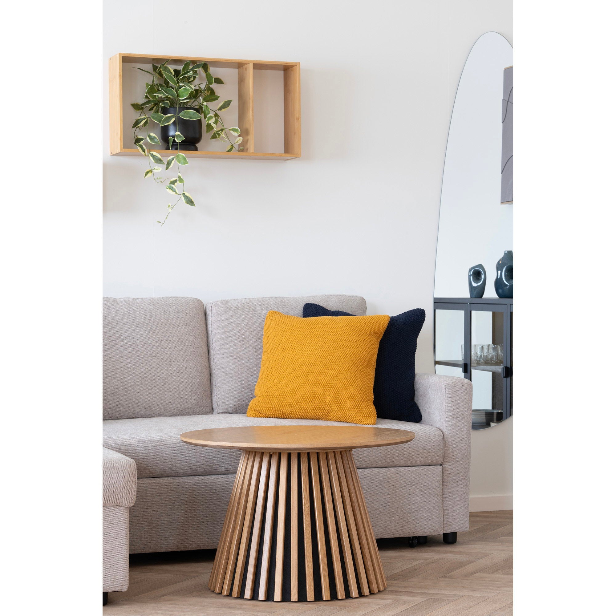 Étagère Ember bambou grand format au-dessus d'un canapé gris avec plante tombante pot noir