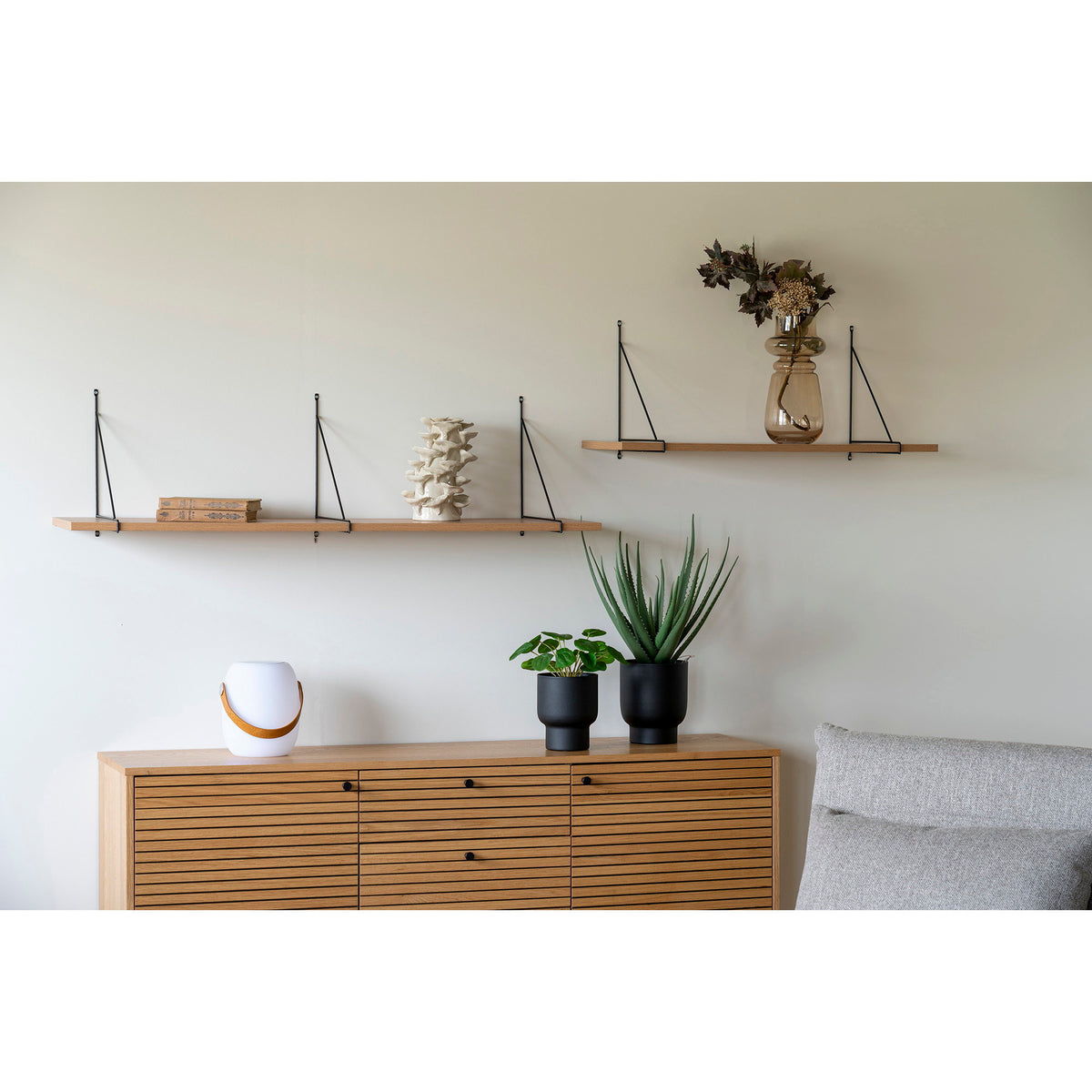 Étagère murale Chiba au-dessus d'un buffet en bois avec deux livres et une sculpture en céramique ivoire près d'une étagère plus courte à deux équerres