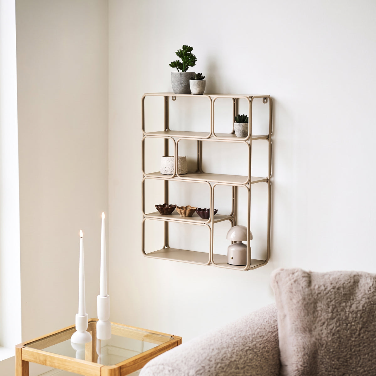 Étagère murale Lanciano beige accrochée au mur d'un salon, garnie de plantes, de coupelles et d'une petite lampe