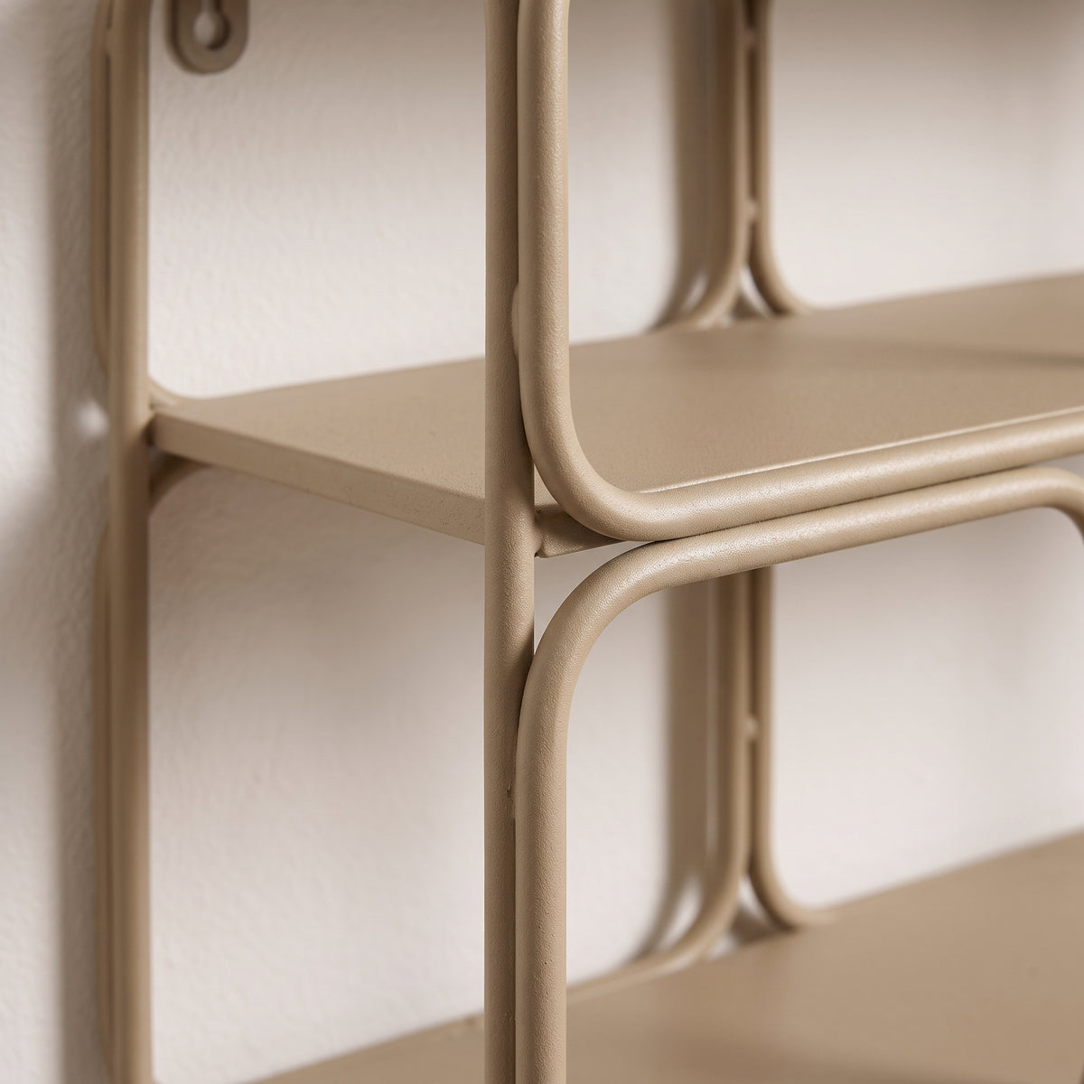 Détail des tubes ronds en métal beige mat et d'un plateau de l'étagère murale Lanciano