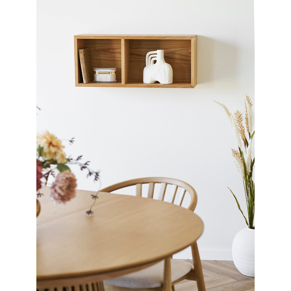 Étagère murale Oshawa en placage chêne garnie d'un livre d'une boîte et d'un vase blanc au-dessus d'une table