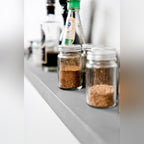 Étagère murale Sliced en béton gris vue de près avec des bocaux d'épices en verre et des bouteilles