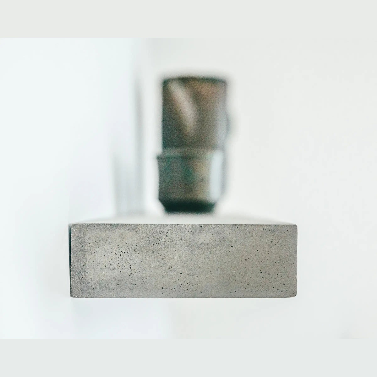 Tranche rectangulaire d'une étagère murale Sliced vue de face en béton plein aux fines bulles d'air avec une tasse floue derrière