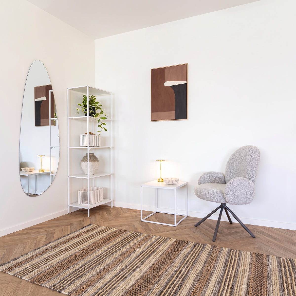 Étagère Vita en acier blanc dans l'angle d'un séjour, près d'un miroir, d'une table d'appoint et d'un fauteuil