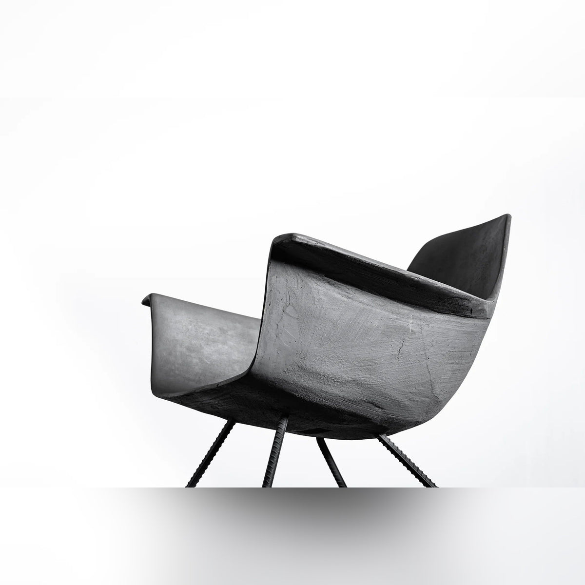 Coque du fauteuil bas Hauteville vue de profil en contre-plongée avec ses pieds en fer à béton