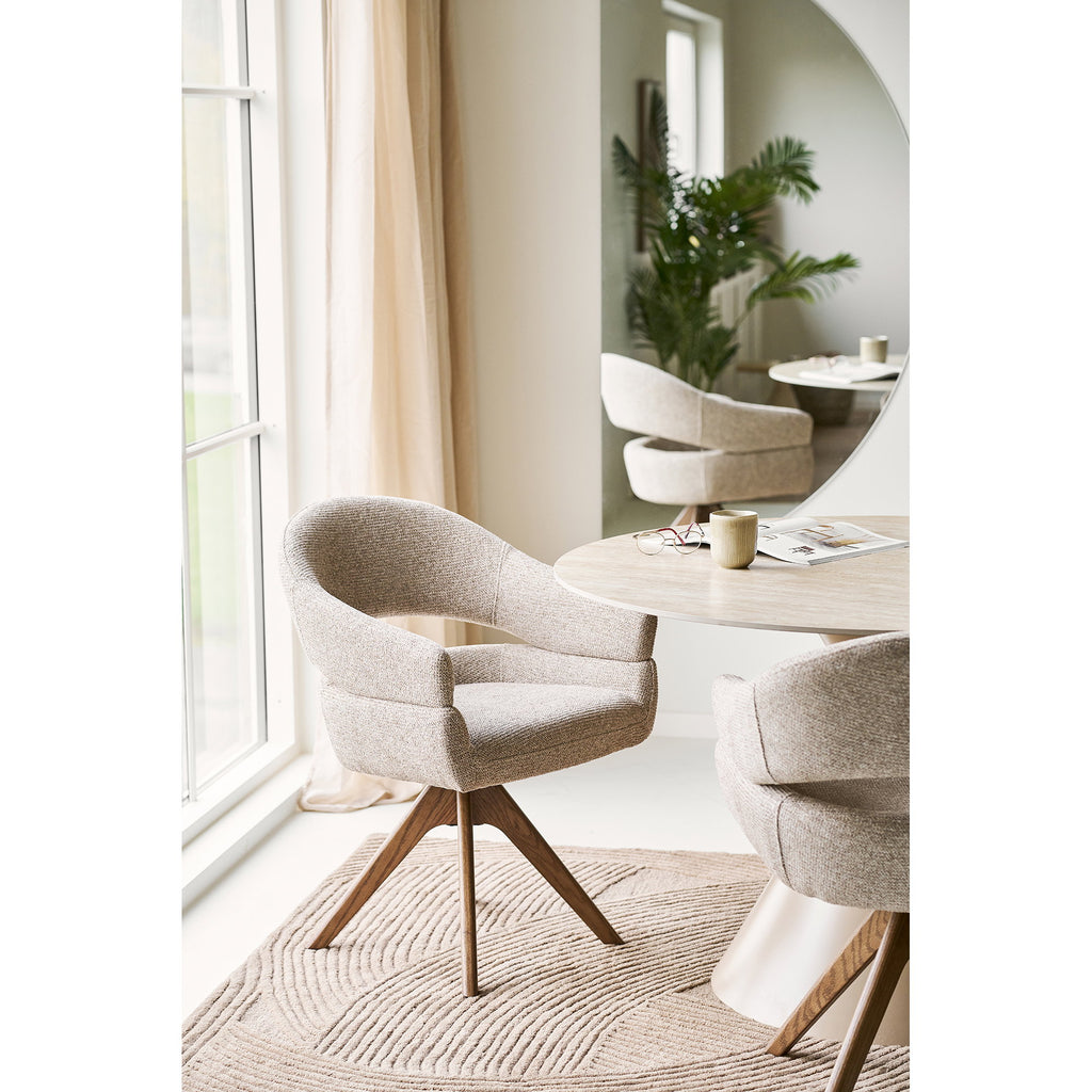 Fauteuil pivotant Dover bouclé sable dans un espace repas lumineux table ovale marbre chêne brun