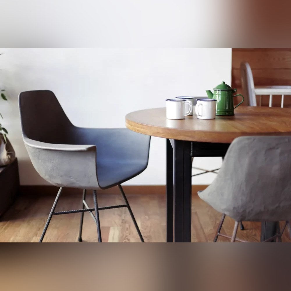 Fauteuil en béton Hauteville gris naturel près d'une table ronde en bois dans un coin repas