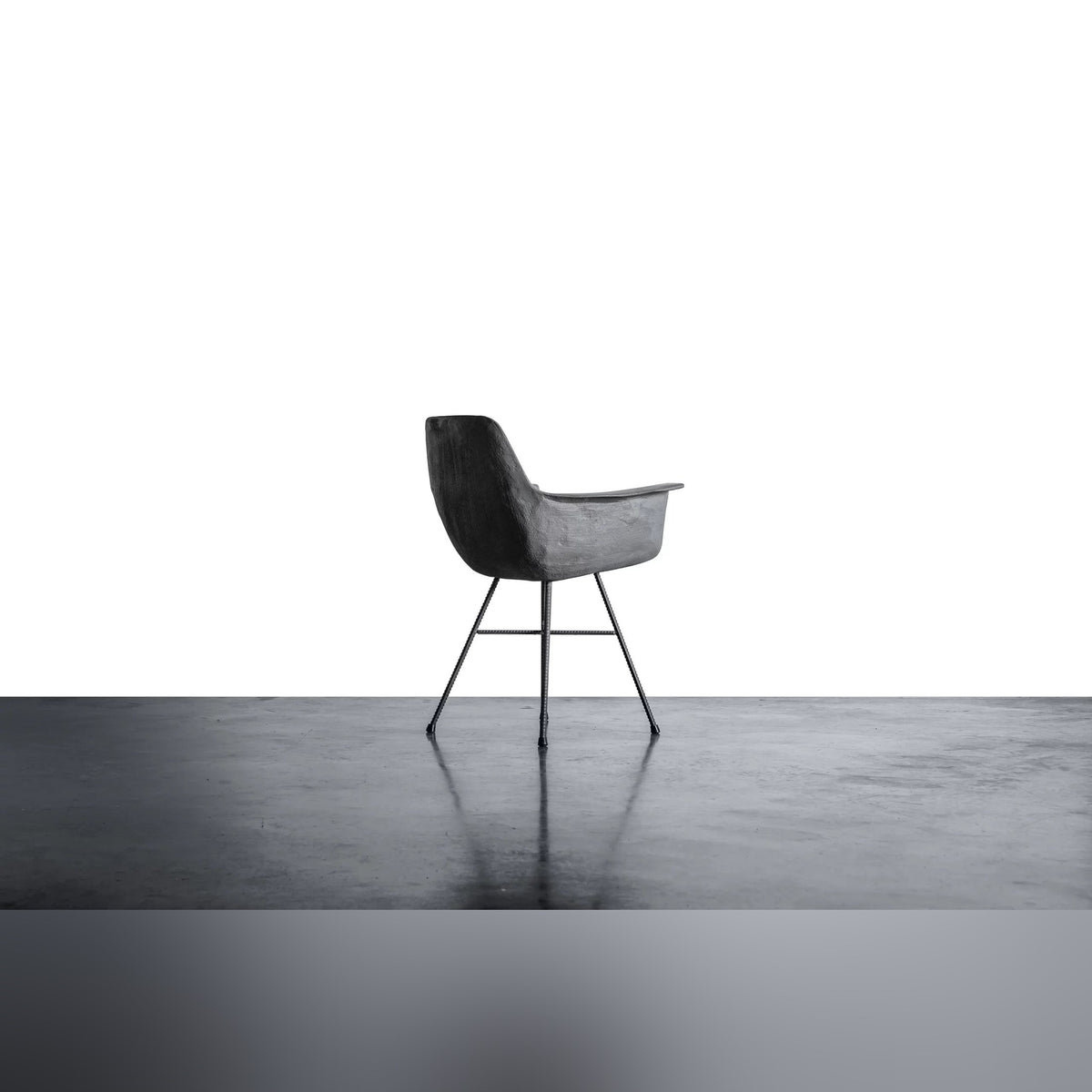 Fauteuil en béton Hauteville vu de profil arrière sur un sol en béton lissé
